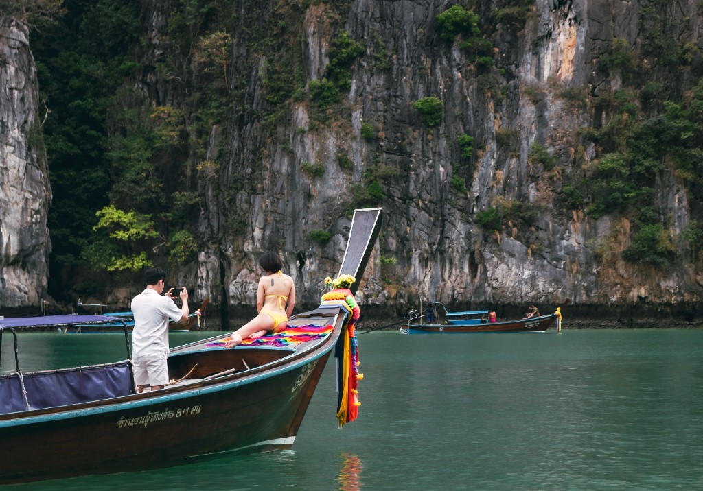 Long-tail boat on turquoise water with limestone cliffs in Thailand